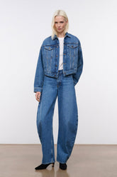 Vintage-wash denim jacket with long sleeves, worn with blue jeans—front view