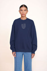 Navy oversized crewneck sweatshirt with small embroidered animal graphic on chest.