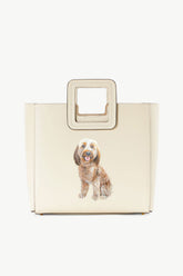 Cream leather tote bag with pet portrait patch and structured square handle detail.