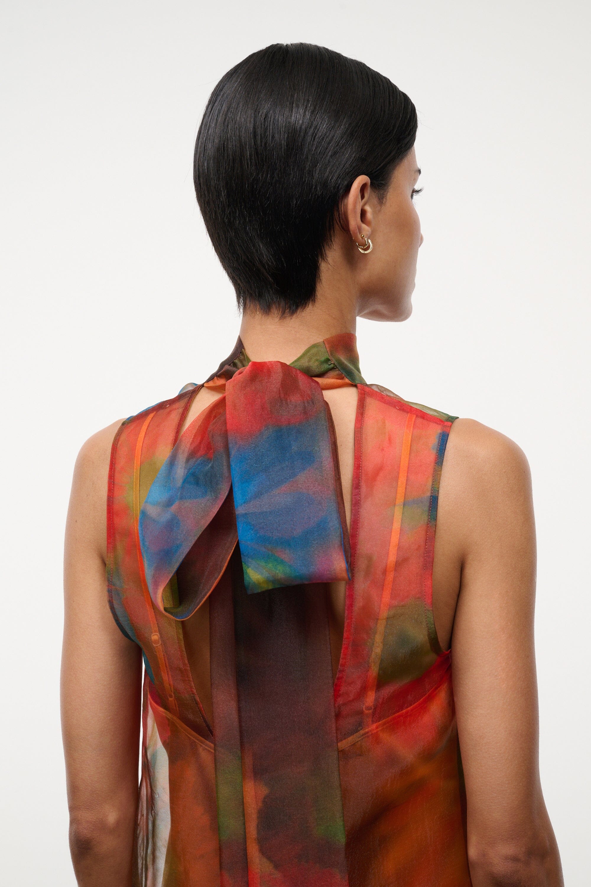 Back view of multi-color sheer mini dress with open back and draped shoulder