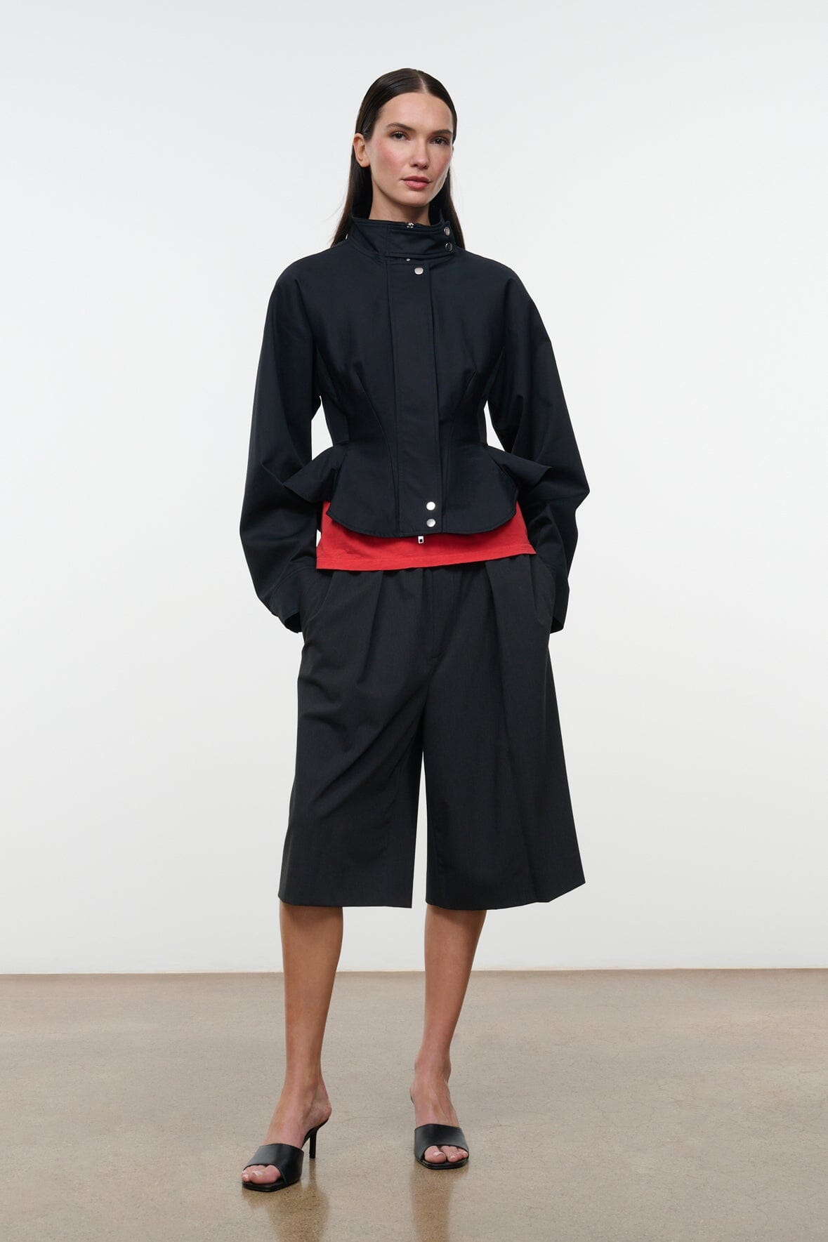 Black cropped jacket with stand collar, snap front, peplum hem over shorts