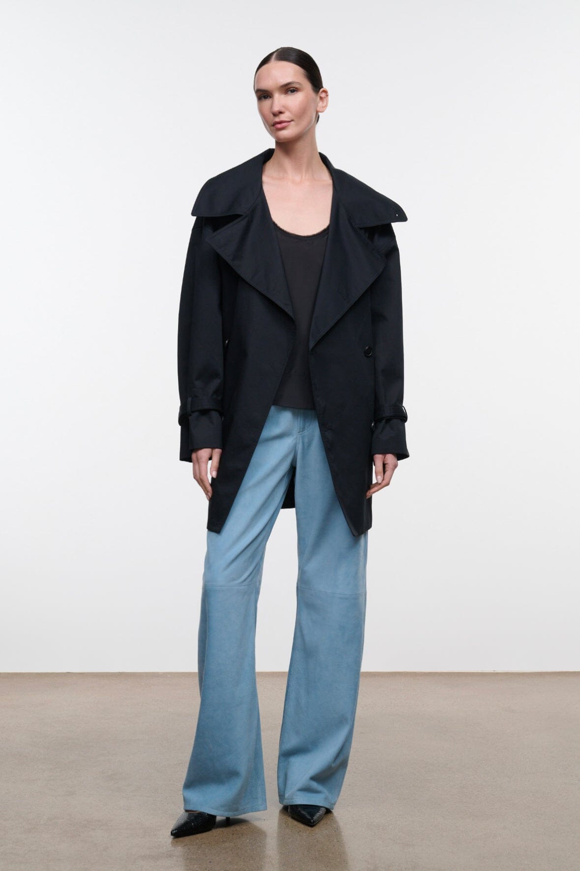 Black open-front jacket with relaxed lapels and buttoned shoulder straps